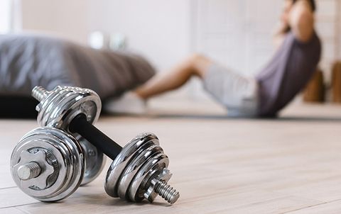 Man doing crunches in bedroom with weights in the foreground